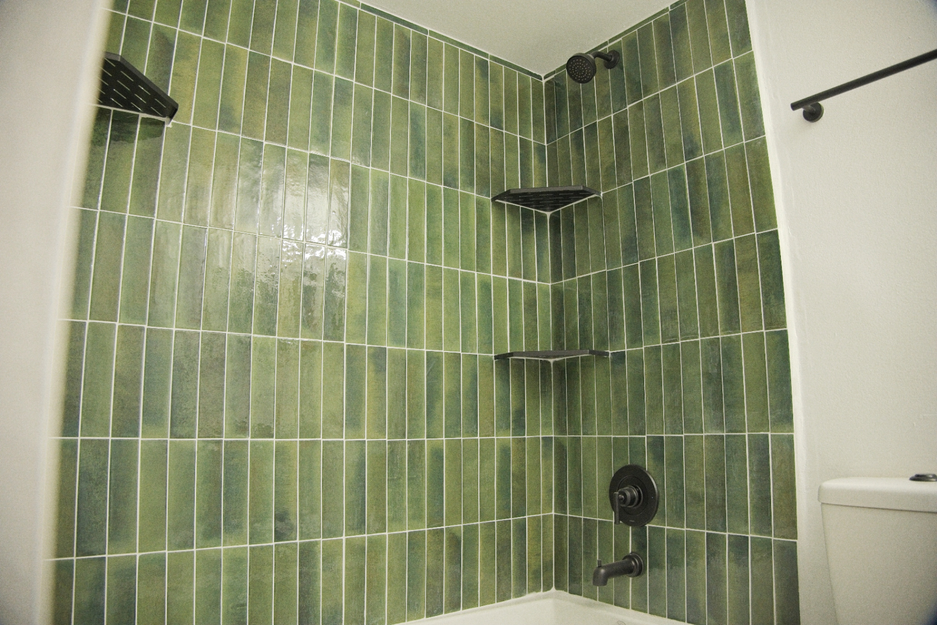 Custom green tile shower with oil-rubbed bronze fixtures